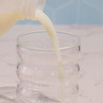 Making kiid coffee in cup. 3 steps pour milk, add kiid coffee, mix and then top with milk